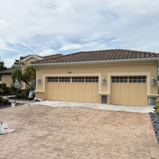 Tile-roof home with tan exterior and garage doors before repainting