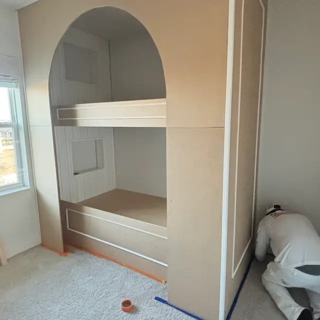 Built-in arched bunk nook being painted in a bedroom
