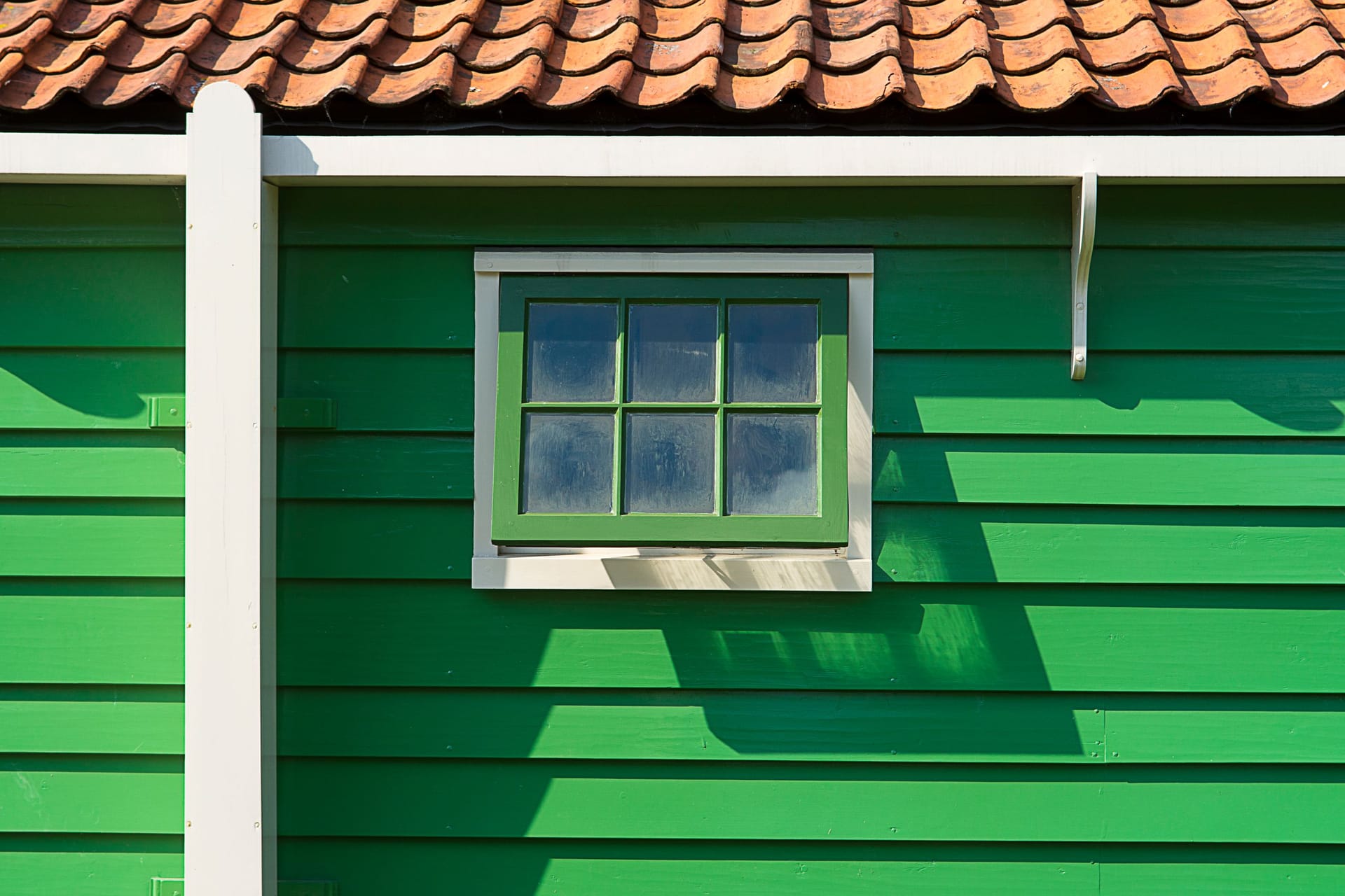 Freshly painted green timber siding with crisp white trim on a house exterior